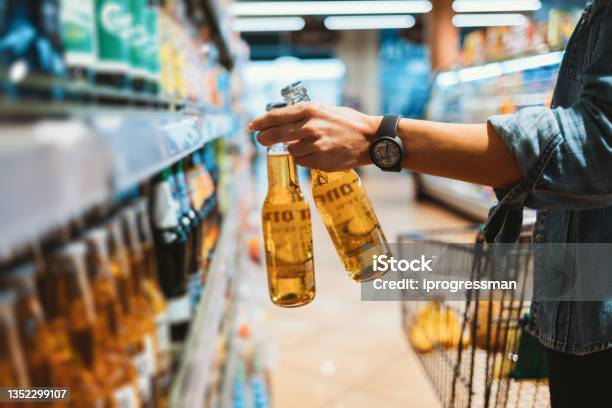 Closeup Of Female Hand Holding Two Glass Bottle Stock Photo - Download Image Now - Alcohol - Drink, Supermarket, Retail