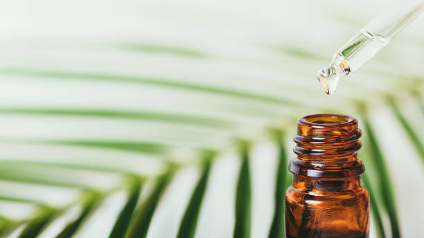 istock Essential oil drop dripping from pipette in amber glass bottle 1352299116