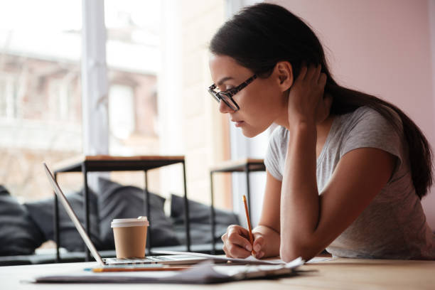 istock Pretty young caucasian woman using laptop computer and writing notes. 1352300534