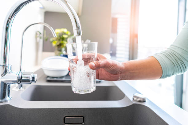 Filling glass of water from the tap Close up of a woman hand filling a glass of water directly from the tap. High resolution 42Mp indoors digital capture taken with SONY A7rII and Zeiss Batis 25mm F2.0 lens drinking water stock pictures, royalty-free photos & images