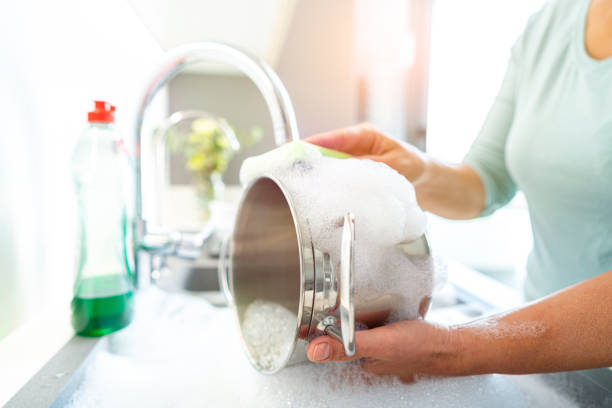 istock Cleaning stainless steel cooking pot with a sponge 1352302497
