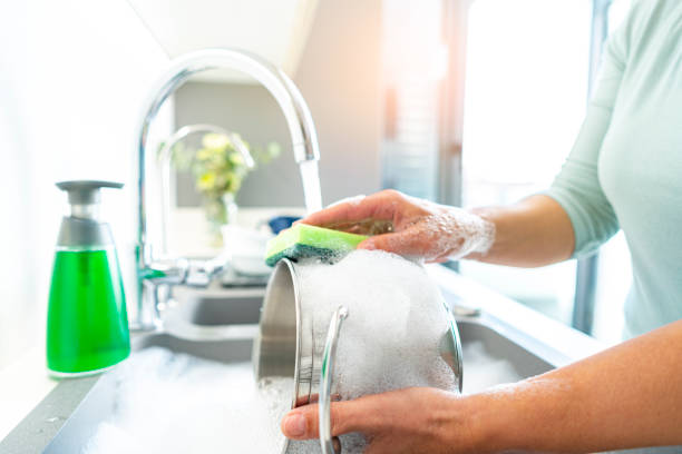 istock Woman cleaning cooking pot with a sponge 1352302498