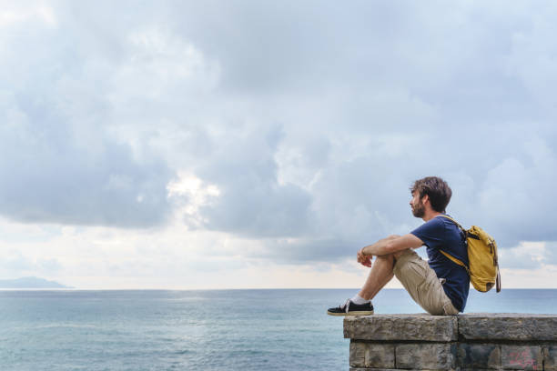 istock Panoramic view of young traveler man sit in a cliff. 1352302584