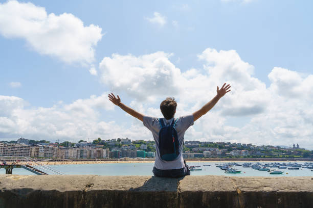 istock Panoramic view of unrecognizable man with arms wide open in a cliff. 1352302628