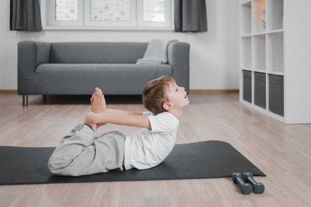 istock Boy child practicing yoga, stretching in dhanurasana exercise, bow pose, working out wearing sportswear, t-shirt, pants/ 1352303423