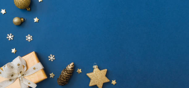 istock Christmas holiday banner background with copyspace. Flat lay frame with christmas balls and gift box on a blue background 1352305107