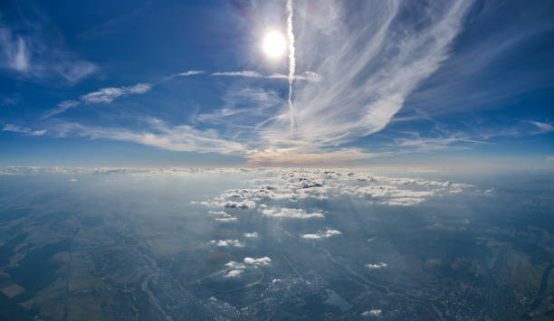 istock Aerial view from airplane window at high altitude of earth covered with white thin layer of misty haze and distant clouds. 1352305411