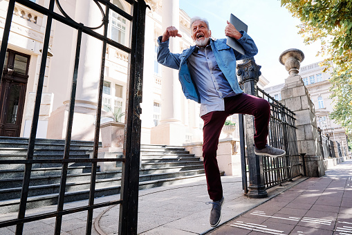 A happy senior student on the retraining program passed the exam and he is jumping with joy and happiness.