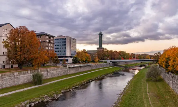 A picture of the Ostrava New City Hall and the Ostravice river during the fall, at sunset.