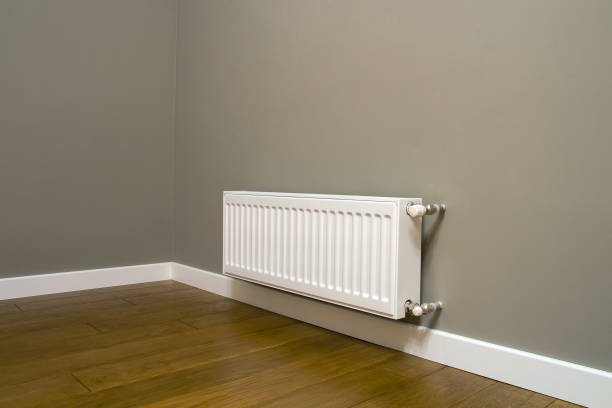 istock White metal heating radiator mounted on gray wall inside a room. 1352309739