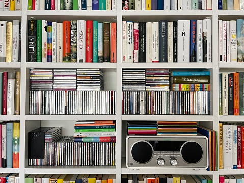 Media player, books and compact discs in white shelves