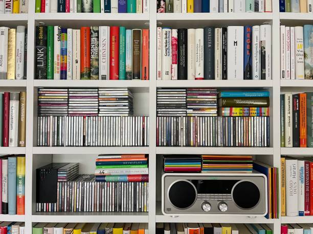 media player, books and compact discs in white shelves - hardcover book audio imagens e fotografias de stock