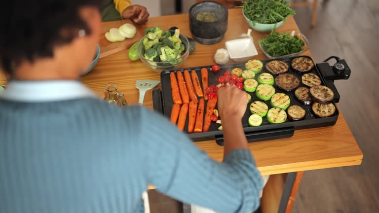 Female friends preparing vegan lunch on electric grill in kitchen at home