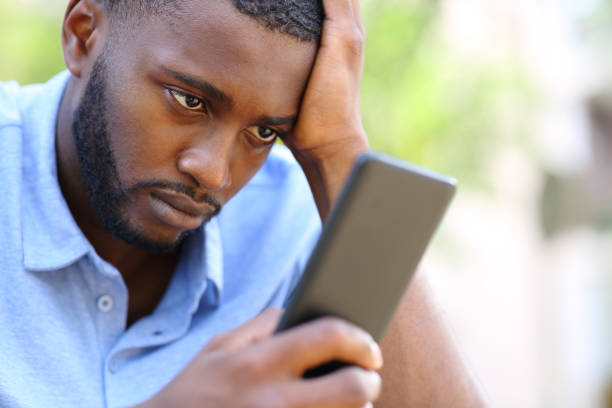 istock Worried man with black skin checking smart phone 1352315799