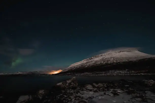 Borealis aurora sweeps over a large lake on a cloudless night in Kilpisjarvi, Lapland, Finland. aurora polaris in green dances across the sky. Scandinavian magic. Saana mountain in fog.