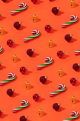 Christmas ornaments and candy canes repetition on orange colored background