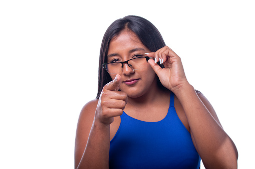 Black woman looking straight ahead with suspicious expression. Latin woman lowering her glasses and suspicious look, looking at camera. Detective look, Girl isolated on all white background.
