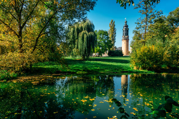 Weimar, Thuringia, Germany - Oktober 10, 2018: View in autumn of the lawns of Park an der Ilm and the bastille tower. Both the park and the City Castle are part of the World Heritage Site.