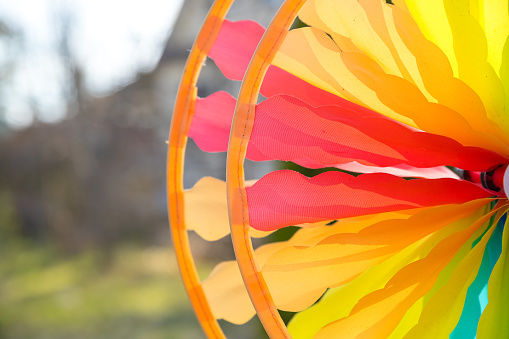Colorful pinwheel flower spinning in the wind in front of a natural green background