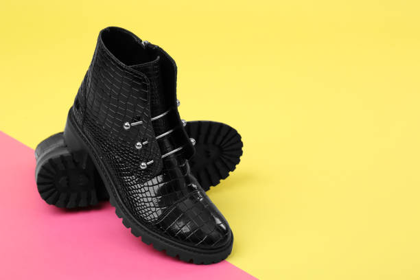 istock Pair of stylish ankle boots on color background. Space for text 1352321635