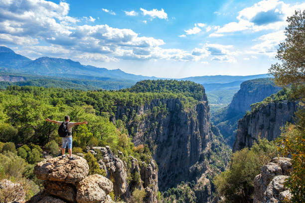 istock Peaceful man with outstretched arms standing on cliff 1352326216