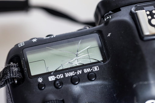 Damaged DSLR camera, broken screen, background with copy space, full frame horizontal composition