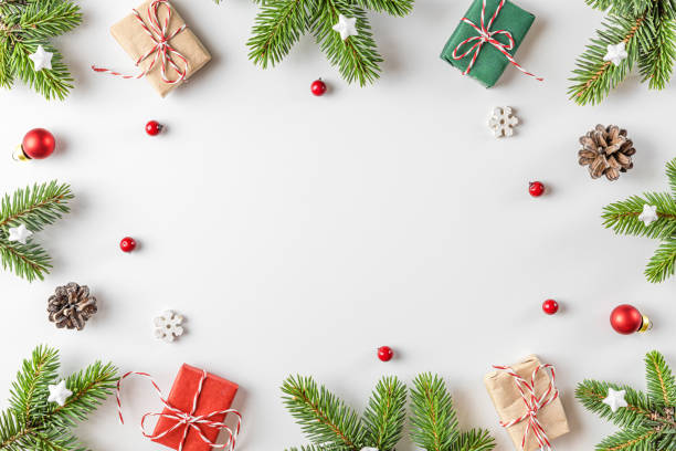istock Christmas composition. Frame made of fir tree branches, decorations, gift boxes, red berries on white background 1352331036