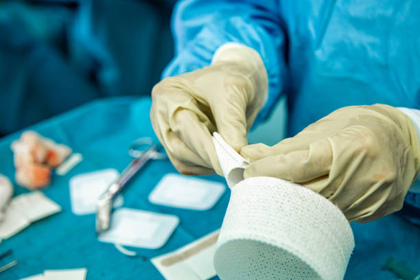 A nurse with latex gloves cuts strips of bandage in preparation to care for an injured person stock photo