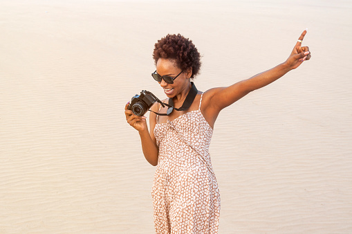 Female tourist enjoys her free time while taking pictures. Latina girl with afro and sunglasses.