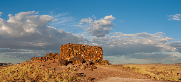 Between 900AD and 1200AD native people inhabited the Painted Desert east of the San Francisco Peaks of Arizona.  In an area so dry it would seem impossible to live, they built pueblos, harvested rainwater, grew crops and raised families.  Their way of life was the key to survival in this harsh landscape.  These people survived here, farming one of the warmest and driest places on the Colorado Plateau.  They developed the skills to farm the land and endure hardship in an area where many would not.  These ancestral Puebloan people used petrified wood not only for tools but also as a building material.  Located on top of a small hill, this structure was built almost entirely of petrified wood and sealed with mud mortar.  These thought-provoking remains bring to mind the innovativeness in building and the environmental challenges faced by these indigenous peoples.  Based on nearby similar buildings, this pueblo was most likely part of a much larger community of 