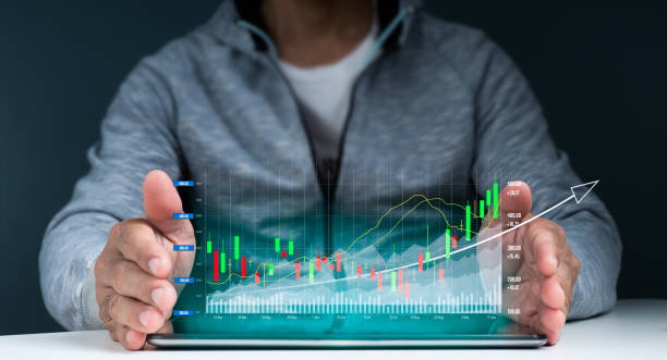 istock A man protects a tablet on the table with both hands. There are images on the screen, and the stock graph is glittering as it reaches its pinnacle. 1352340078
