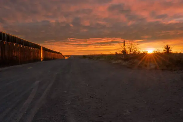 Photo of Mexico/United States Border wall between El Paso Texas and Juárez Chihuahua Mexico at dusk with dramatic sunset cloudscape