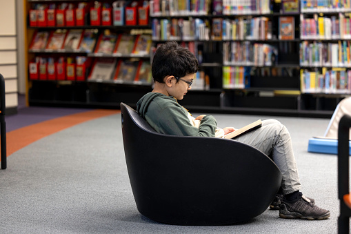High quality stock photos of 10-year-old boy using a public library.