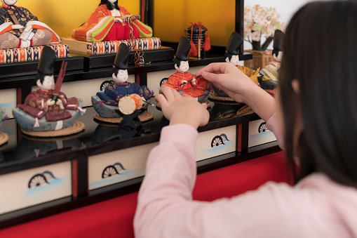 Girl decorating the room with Hina dolls.