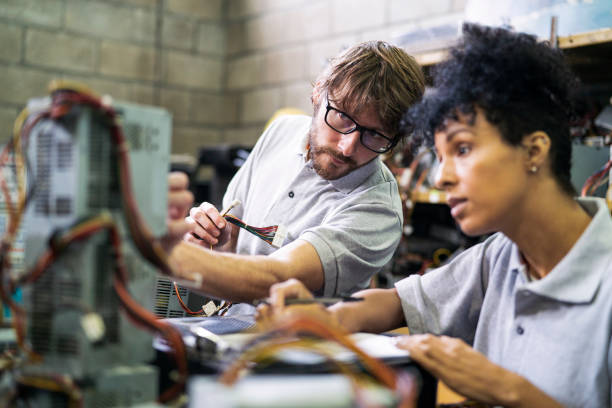 Male and female warehouse worker taking inventory of computer components in recycling plant stock photo