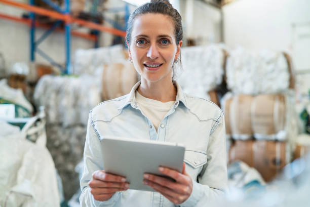 istock Portrait of smiling female worker holding digital tablet while standing inside recycling centre during daytime 1352364261