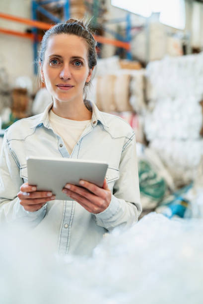 istock Portrait of smiling female worker holding digital tablet while standing inside recycling centre during daytime 1352364266