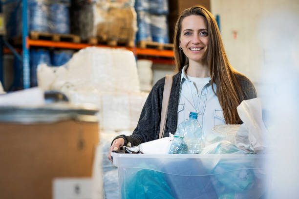 istock Smiling woman carrying container with plastic classified garbage at recycling centre 1352365111