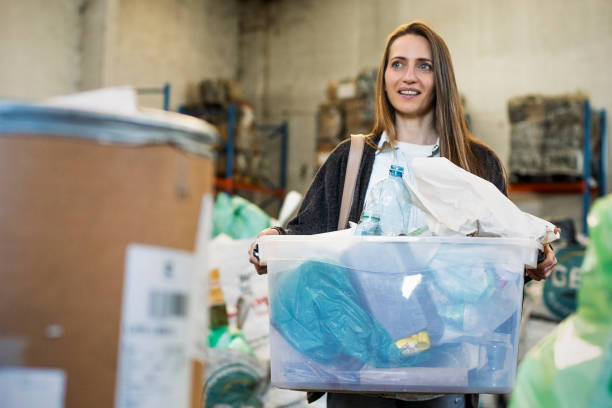 istock Smiling woman carrying container with plastic classified garbage at recycling centre 1352365131