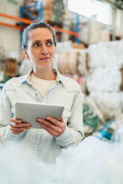 istock Portrait of smiling female worker holding digital tablet while standing inside recycling centre during daytime 1352365196