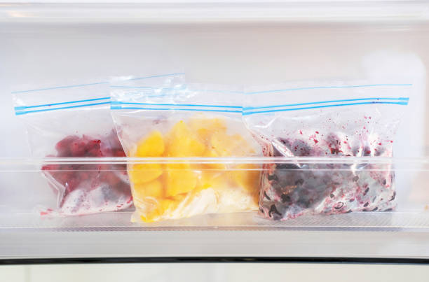 gefrorene früchte und beeren in plastiktüten im gefrierschrank nahaufnahme. - refrigerator healthy eating mango fruit stock-fotos und bilder