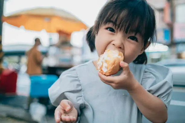 Little girl is very happy to eat cream puffs