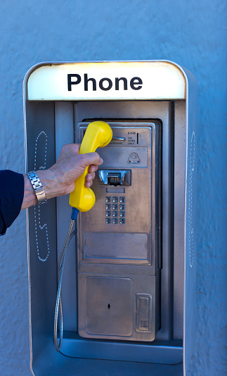 Man's Hand Picking Up Old-Fashioned Pay Phone