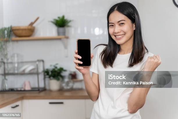 Attractive Young Asian Woman Holding Smartphone With Blank Screen Stock Photo - Download Image Now