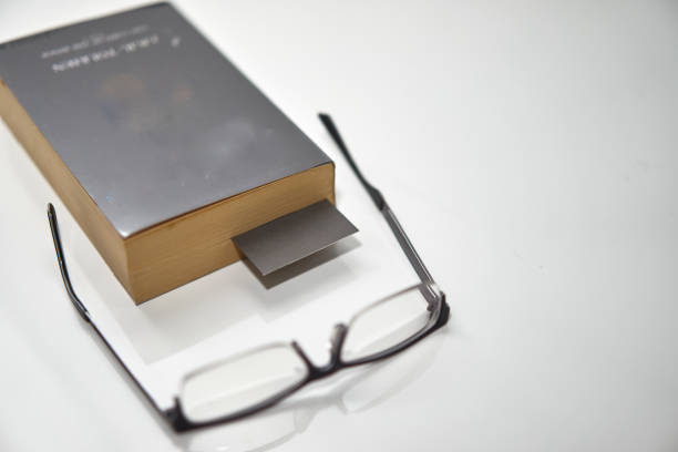 Bookmark in old book on white high angle view with copy space with read glasses