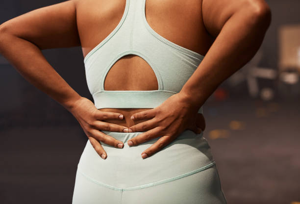 aufnahme einer frau mit rückenschmerzen beim training in einem fitnessstudio - back rear view pain backache stock-fotos und bilder