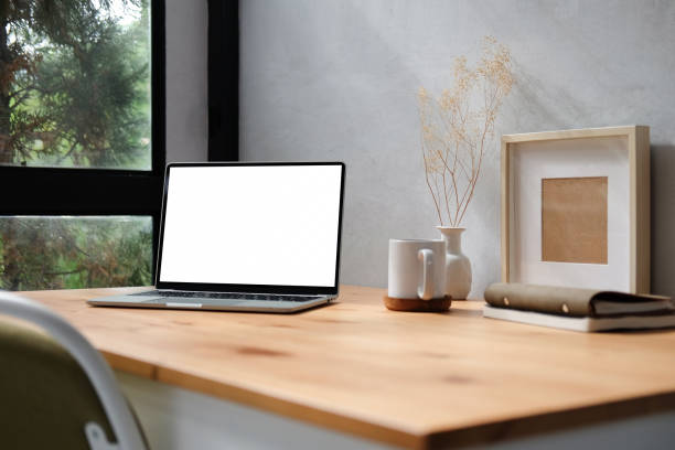 istock Computer laptop with blank display, pencil holder, coffee cup and houseplant on wood table. 1352381156