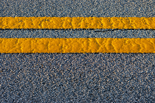 Overhead shot of double yellow lines on an asphalt road.