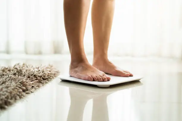 young woman standing on digital weight scale