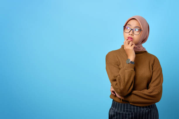 istock Pensive young Asian woman looks seriously thinking about a question on blue background 1352394555